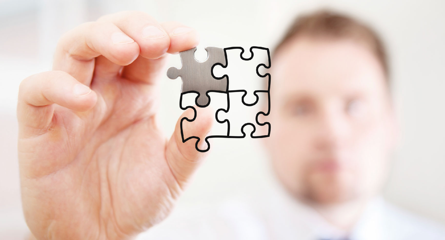 Hand hält gezeichnete Puzzleteile vor einem unscharfen Mann
