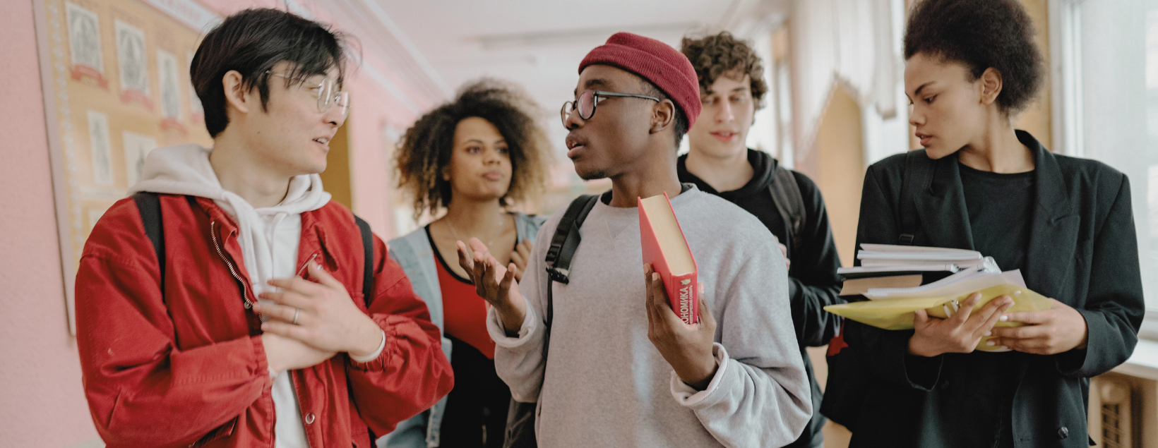 Gruppe Studierender mit Büchern unterhält sich im Flur